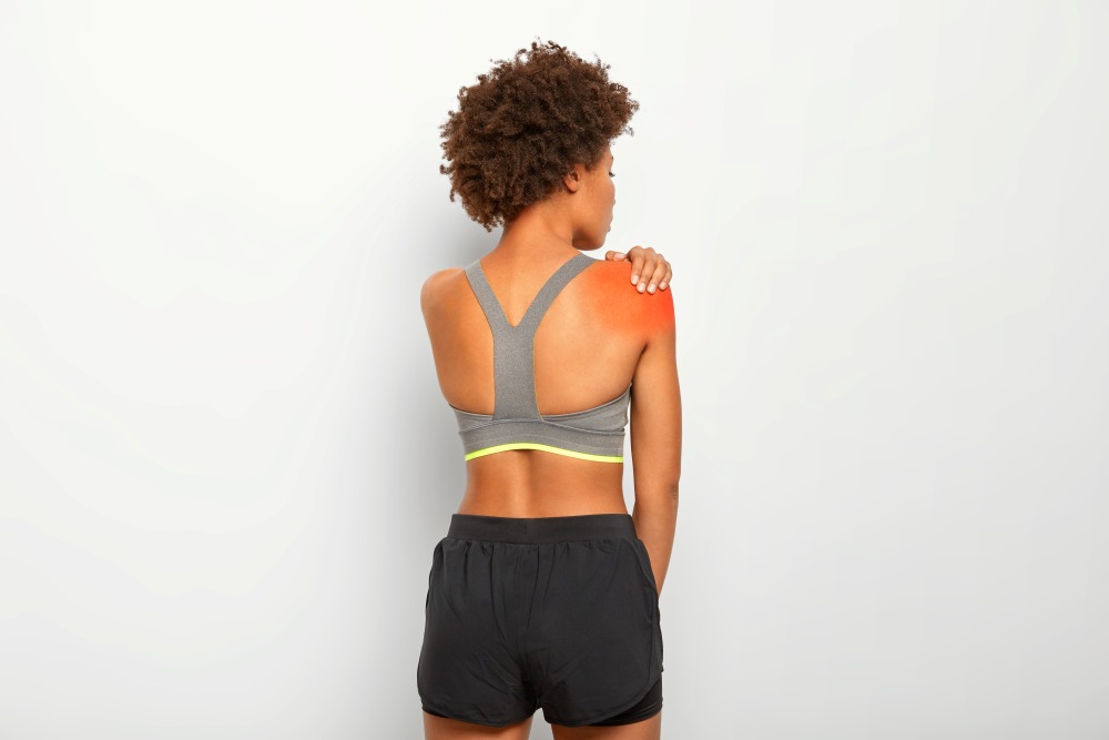 Woman touches shoulder stands back being injured